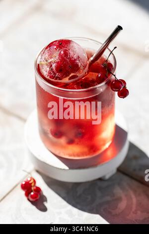 Beeren-Limonade im Glas mit Eiskugeln mit gefrorenen roten Johannisbeerbeeren Stockfoto