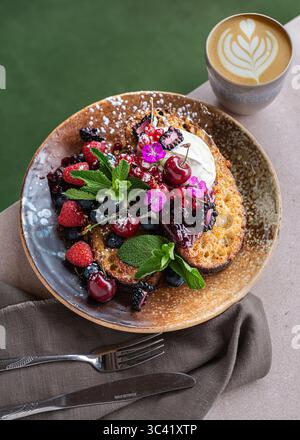 Ein Teller französischer Toast mit frischen Beeren und Schlagsahne, serviert als köstlicher und optisch ansprechender Brunch. Hausgemachte süße Frühstückskappe Stockfoto