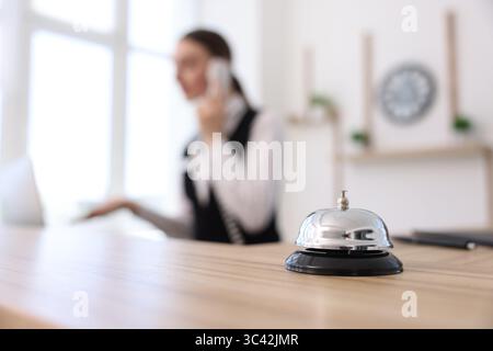Der Rezeptionist spricht telefonisch mit dem Kunden im Hotel, konzentriert sich auf die Serviceklingel Stockfoto