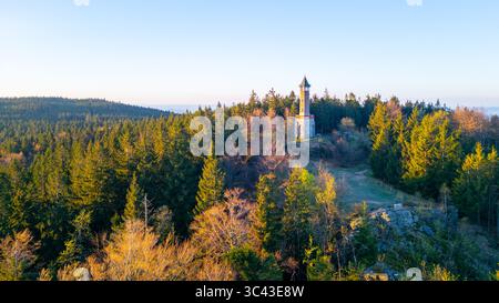 An einem sonnigen Frühlingsmorgen erhebt sich der Stepanka Aussichtsturm majestätisch auf den grünen Hügeln in Korenov, umgeben von üppigen Wäldern und einem klaren blauen Himmel. Stockfoto