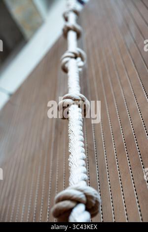 Nahaufnahme eines weißen Seils, das an einer Holzwand hängt und ein nautisches oder dekoratives Element schafft Stockfoto