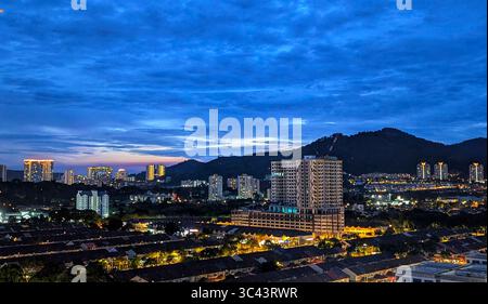 Die atemberaubende Fotografie bei Sonnenuntergang entfaltet sich in den Batu Caves Malaysia, wo der Himmel der goldenen Stunde auf Stadtturmlichter und Straßenbeleuchtung trifft. Von Stockfoto