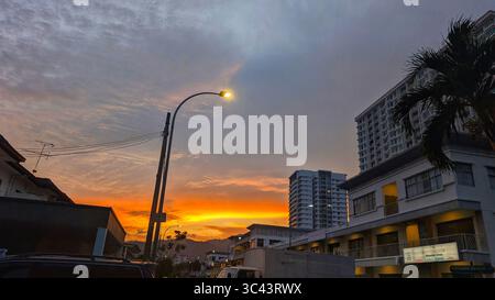 Die atemberaubende Fotografie bei Sonnenuntergang entfaltet sich in den Batu Caves Malaysia, wo der Himmel der goldenen Stunde auf Stadtturmlichter und Straßenbeleuchtung trifft. Von Stockfoto