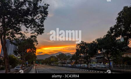 Die atemberaubende Fotografie bei Sonnenuntergang entfaltet sich in den Batu Caves Malaysia, wo der Himmel der goldenen Stunde auf Stadtturmlichter und Straßenbeleuchtung trifft. Von Stockfoto