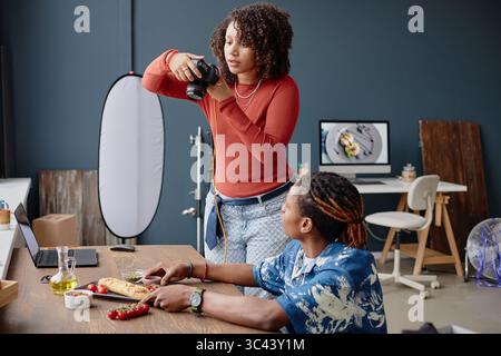 Junge Erwachsene fotografieren Lebensmittel in professioneller Studio-Umgebung Stockfoto