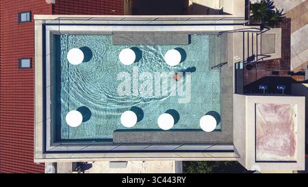 Aus der Vogelperspektive eines Schwimmers, der anmutig durch das türkisfarbene Wasser eines Dachpools gleitet, umgeben von unberührten weißen Plattformen, Split-Dalma Stockfoto