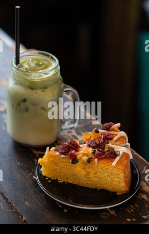 Erfrischender Matcha-Latte, serviert mit einem Stück leckeren hausgemachten Kuchen. Eine gemütliche und ästhetische Einrichtung im Café-Stil, perfekt für einen entspannenden Urlaub oder af Stockfoto