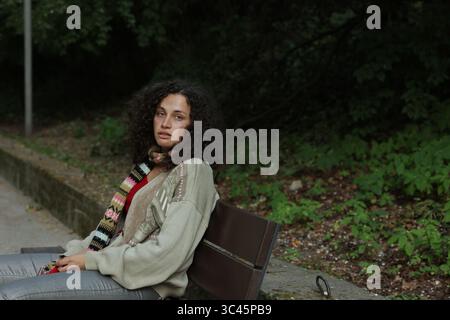 Obdachlose Frau, die auf einer Bank im Park sitzt Stockfoto