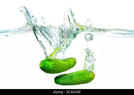 Gurken spritzen in klares Wasser und erzeugen dynamische Blasen und Wellen. Stockfoto