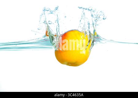 Dynamisches Spritzen einer frischen Aprikose in klares Wasser, das einen lebhaften Orangenton und einen aufregenden Moment voller Bewegung und Energie einfängt. Stockfoto