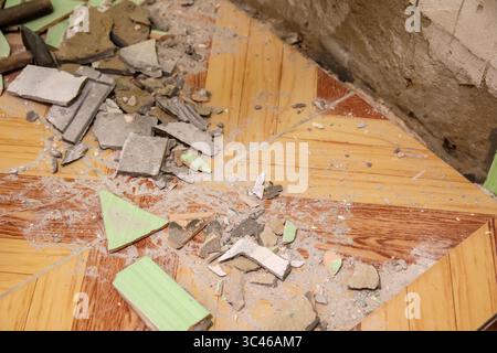 Ein ergreifendes Bild eines ruinierten Badezimmers, in dem ein einst leuchtend gelb-grün gefliester Boden und eine passende Wand den Lauf der Zeit und Vernachlässigung offenbaren Stockfoto