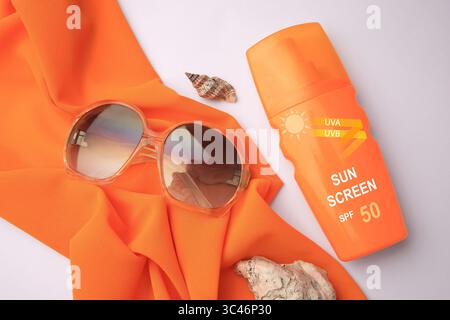 Sonnencreme in der Flasche, Sonnenbrille und Tuch auf weißem Hintergrund, Draufsicht. Sonnenschutzmittel Stockfoto