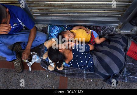 2. Juli 2018 - Matamoros, Mexiko - 2. Juli 2018 - Matamoros, Mexiko - Asylsuchende schlafen auf der Gateway International Bridge und warten darauf, von Mexiko aus in die USA zu überqueren. Ingrid Perdomo, 18, und ihr 1-jähriger Sohn Jose Luis machen ein Nickerchen in glühender Hitze. Sie kam mit ihrem Gefährten Luis Miguel, 32 Jahre alt, aus Honduras, wo sie die schwierige 3-monatige Reise machten. Er sagte, er floh vor Angst und weinte viel vor Angst über seine Vergangenheit. Seine Ex-Frau fing an, mit einem Bandenmitglied auszugehen, und die Gang zündete sein Haus an und tötete seine beiden Kinder darin. Er floh in die Berge, um Sicherheit zu suchen, wo er Ingrid traf und sie es hatten Stockfoto