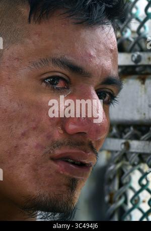 2. Juli 2018 - Matamoros, Mexiko - 2. Juli 2018 - Matamoros, Mexiko - Luis Miguel Montimo, 32 aus Honduras weint, während er mit Freiwilligen aus humanitärer Hilfe von Asociacion Civil Ayudandoles spricht. Seine Gefährtin Ingrid Perdomo, 18 Jahre alt, und ihr einjähriger Sohn Jose Luis machen ein Nickerchen in glühender Hitze. Sie machten die schwierige 3-monatige Reise. Er sagte, er floh vor Angst und weinte viel vor Angst über seine Vergangenheit. Seine Ex-Frau fing an, mit einem Bandenmitglied auszugehen, und die Gang zündete sein Haus an und tötete sein Stockfoto