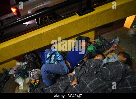 2. Juli 2018 – Matamoros, Mexiko – 2. Juli 2018 – Matamoros, Mexiko – Ingrid Perdomo, 18 Jahre alt und ihr 1-jähriger Sohn Jose Luis, 32 Jahre alt, schlafen auf der Brücke. Asylsuchende schlafen auf der Gateway International Bridge und warten darauf, von Mexiko aus in die USA zu überqueren. Sie kamen aus Honduras, wo sie die schwierige 3-monatige Reise machten. Er sagte, er floh vor Angst und weinte viel vor Angst über seine Vergangenheit. Seine Ex-Frau fing an, mit einem Bandenmitglied auszugehen, und die Gang zündete sein Haus an und tötete seine beiden Kinder darin. Er floh in die Berge, um Sicherheit zu suchen, wo er Ingrid traf und sie ein weiteres Kind hatten. Stockfoto