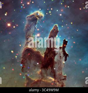 12. Juli 2018: Der Adlernebel, auch bekannt als Messier 16, enthält den jungen Sternhaufen NGC 6611. Es ist auch der Ort der spektakulären Sternentstehungsregion, bekannt als Säulen der Schöpfung, die sich im südlichen Teil des Adlernebels befindet. Dieses neue Verbundbild zeigt die Region um die Säulen, die etwa 5.700 Lichtjahre von der Erde entfernt sind. Das Bild kombiniert Röntgendaten vom Chandra X-ray Observatory der NASA mit optischen Daten des Hubble Space Telescope. Das optische Bild, das mit Filtern aufgenommen wurde, um das interstellare Gas und den Staub hervorzuheben, zeigt staubigen braunen Nebel, der in A getaucht ist Stockfoto