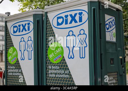 Zwei tragbare Toiletten mit der Marke „DIXI“ werden im Freien gezeigt. Sie haben große blaue und grüne Logos mit männlichen und weiblichen Figuren und Text in niederländischer Werbeaktion Stockfoto