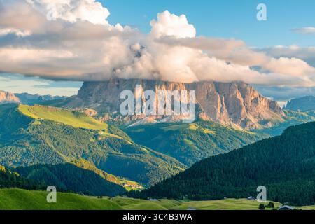 Langkofer Berggipfel, teilweise bedeckt von dramatischen Wolken über dem üppig grünen Alpental in den italienischen Dolomiten Alpen, Seiser Alm, Trentino Alto Stockfoto
