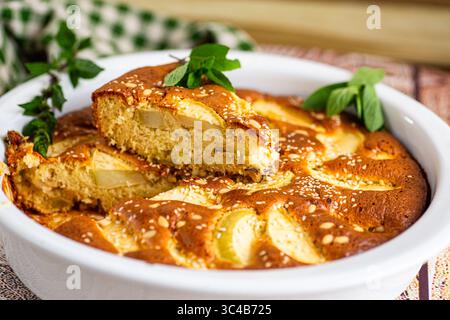 Hausgemachte charlotte mit Äpfeln und Sesamstreuseln in einer weißen Form. Stockfoto