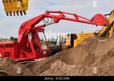 7. September 2024 - Friesland-Niederlande: Zwei klassische Yumbo-Bagger, die auf einem Sanddepot arbeiten, mit sichtbaren Raupenketten, mechanischen Armen A Stockfoto