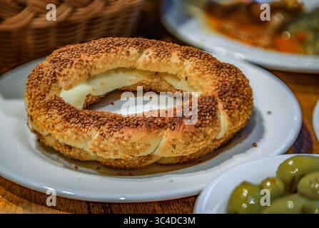 Getoastetes türkisches Sesamsimit mit geschmolzenem Käse, traditionellem Streetfood-Bagel, serviert mit Oliven in einem Restaurant zum Frühstück, Istanbul, Truthahn Stockfoto