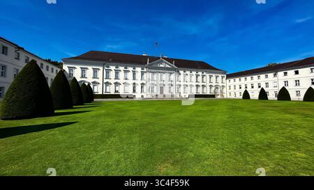 Schloss Bellevue in Berlin, die offizielle Residenz des Bundespräsidenten, von vorne gesehen mit seiner neoklassizistischen Fassade und gepflegtem Rasen. Stockfoto