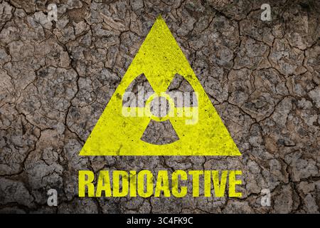Gelbes radioaktives Zeichen auf gerissener trockener Erde, Draufsicht. Radiologische Verschmutzung Stockfoto