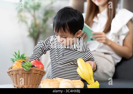 Gesunde Ernährung. Kind entdeckt Obst und Snacks mit Mutter. Stockfoto