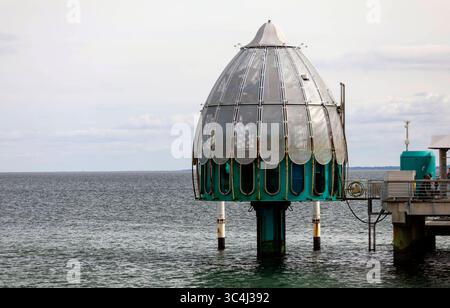 Tauschgondel an der Seebrücke Sellin, einer Seebrücke im Ostseebad Sellin auf der Insel Rügen. Eine Tauchgondel besteht aus einer mit Fenstern ausgestatteten Besuchergondel, die Sitzplätze und einen Maschinentisch enthält, sowie einem zentralen Pfeiler, an dem sie ins Wasser und zurück fährt. Sie ist im Gegensatz zu einer Taucherglocke rundum geschlossen und als Druckkammer ausgelegt. Sellin, 28.07.205 *** Tauchbahn am Sellin Pier, einem Pier im Ostseebad Sellin auf der Insel Rügen Eine Tauchbahn besteht aus einer mit Fenstern ausgestatteten Besuchergondel, in der sich ein Stockfoto