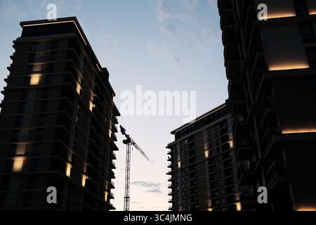 Blick zwischen Hochhäusern mit einem Baukran in Belgrad Waterfront bei Sonnenuntergang. Stockfoto
