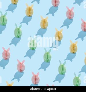 Nahtloses Ostermuster mit pastellfarbenen Papierhasen und Schatten auf hellblauem Hintergrund Stockfoto