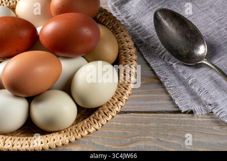 Ein charmantes rustikales Stillleben mit frisch gelegten Hühnereiern, ordentlich auf einer strukturierten Leinenserviette angeordnet, mit einem antiken Löffel neben dem Stockfoto