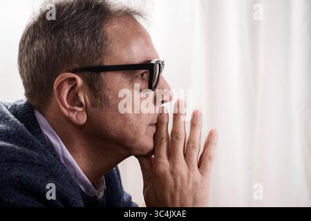 Introspektives Profilporträt eines ernsten Mannes mittleren Alters mit der Hand am Kinn, der eine schwierige Entscheidung erwägt oder unter Angst leidet. Stockfoto