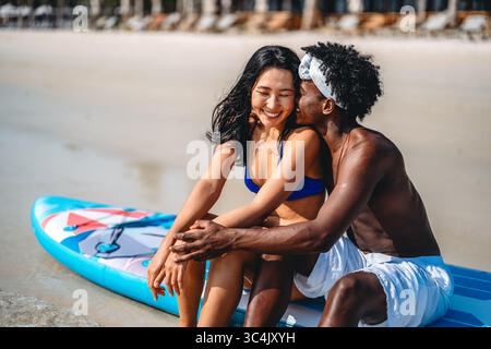 Interrassisches Paar, das einen romantischen Strandurlaub genießt und Liebe, Lachen und Zweisamkeit genießt Stockfoto