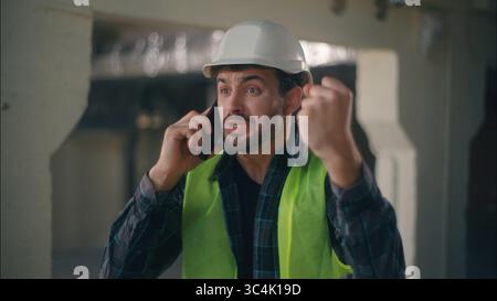 Wütender kaukasischer Vorarbeiter spricht Handy im Bauingenieur männlich schreiend wütender Inspektor Mann streitet Handy-Anruf Stockfoto