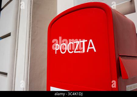 Ein roter polnischer Briefkasten mit der Aufschrift „Poczta“, der an einem sonnigen Tag draußen liegt Stockfoto