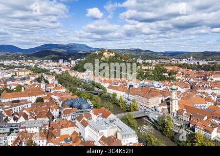 Aus der Vogelperspektive auf Graz und die Mur, die sich durch die Stadt schlängelt, mit Blick auf den Schlossberg und seinen historischen Uhrenturm, Graz, Steiermark, Österreich. Stockfoto
