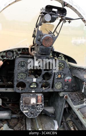 Detaillierte Ansicht eines verlassenen Flugzeugcockpits mit abgenutzten Instrumentenbrettern und Steuerungssystemen in einer rustikalen Umgebung, aufgenommen an einem bewölkten Tag mit Stockfoto