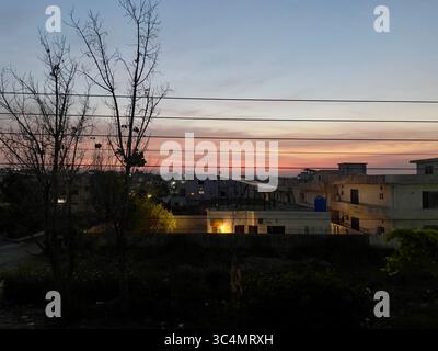 Eine ruhige Vorstadtszene vor Sonnenaufgang, mit pastellfarbenen Himmeln und tiefen Schatten, die die Stille des frühen morgens hervorheben. Stockfoto