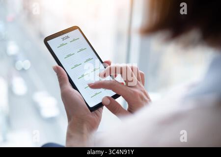 Nahaufnahme Einer Frau, die Ein Smartphone hält und den Kalender 2026 anzeigt Stockfoto