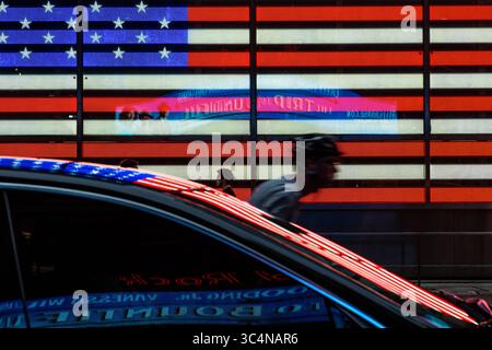 Die hellroten und weißen Streifen der amerikanischen Flagge spiegeln sich auf den Karosserien der Autos am Times Square wider. Stockfoto