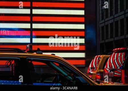 Die hellroten und weißen Streifen der amerikanischen Flagge spiegeln sich auf den Karosserien der Autos am Times Square wider. Stockfoto