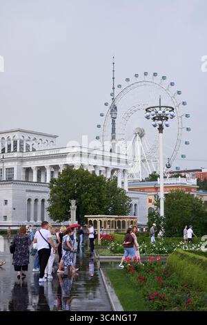 Ausstellung der Errungenschaften der Volkswirtschaft (VDNKh) mit Menschen im Vordergrund und einem Riesenrad und einem hohen Fernsehturm in der Ferne Stockfoto