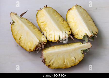 Reife Ananas, frisch in vier saftige Scheiben geschnitten, ruht auf hölzernem Hintergrund. Köstliche Ananas comosus Frucht für gesunde Ernährung und lebendiges Rezept Stockfoto