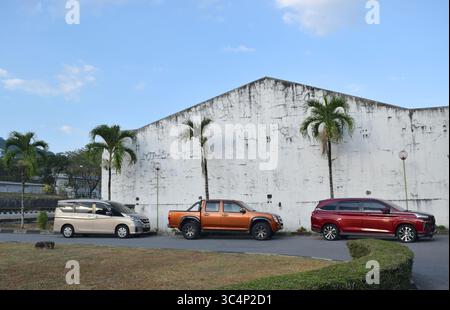 Geparkte Autos an der weißen Wand mit Palmen auf blauem Himmel Hintergrund. Stockfoto
