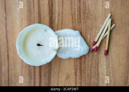 Blick von oben auf verbrannte Kerze, unbeleuchtet, mit verstreuten Streichhölzern und Wachs Tropfen auf einem hölzernen Hintergrund. Stockfoto