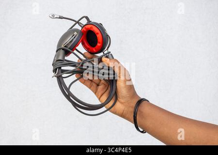 Nahaufnahme einer weiblichen Hand, die Vintage-Kopfhörer mit Kabel mit Mikrofon hält. Retro-Audiogerät. Musik- und Soundtechnologie. Klassischer Hörzugriff Stockfoto