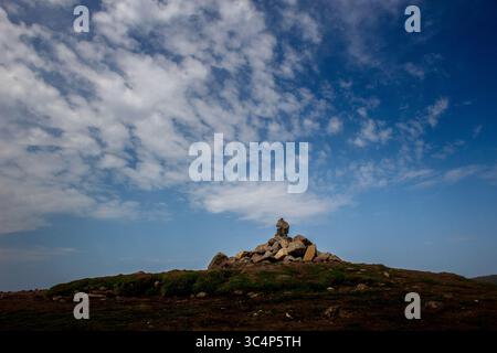 Felsbrocken auf dem Conic Hill bei Balmaha am Ufer des Loch Lomond, Schottland. Schlaue Wolken ziehen über sich Stockfoto
