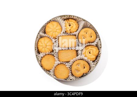 Dänische Butterkekse in Dosenweiß Hintergrund. Eine klassische Auswahl an dänischen Butterkeksen, die in einer runden Dose ordentlich in Pappbecher angeordnet sind. Die Kuh Stockfoto