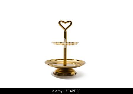 Zweistufiger Goldener Kuchenständer, Weißer Hintergrund. Ein glänzendes, goldenes, zweischichtiges Serviertablett mit einem herzförmigen Griff, isoliert auf weißem Hintergrund. Perfekt für Stockfoto